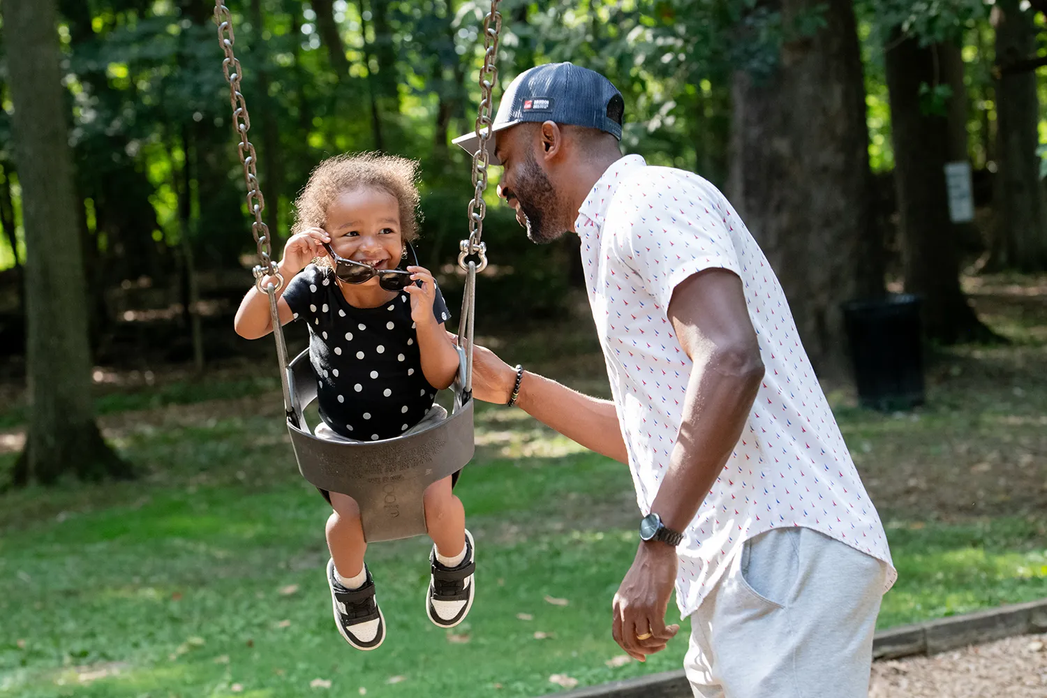 Jon pushing his daughter on the swing set
